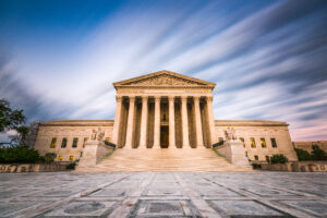 Majestic view of the U.S. Supreme Court building at dusk, with grand columns and a marble facade. A dramatic sky creates a serene and authoritative tone.